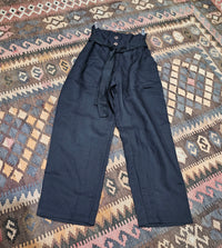 "High-waisted, super baggy cropped pants in a hand-dyed cotton linen blend with front pleats, pockets, zip closure, and a waist-accentuating belt."