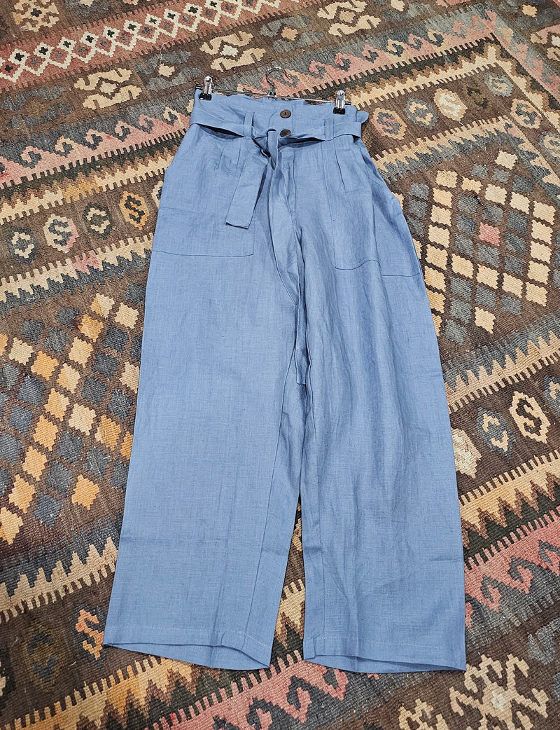 "High-waisted, super baggy cropped pants in a hand-dyed cotton linen blend with front pleats, pockets, zip closure, and a waist-accentuating belt."