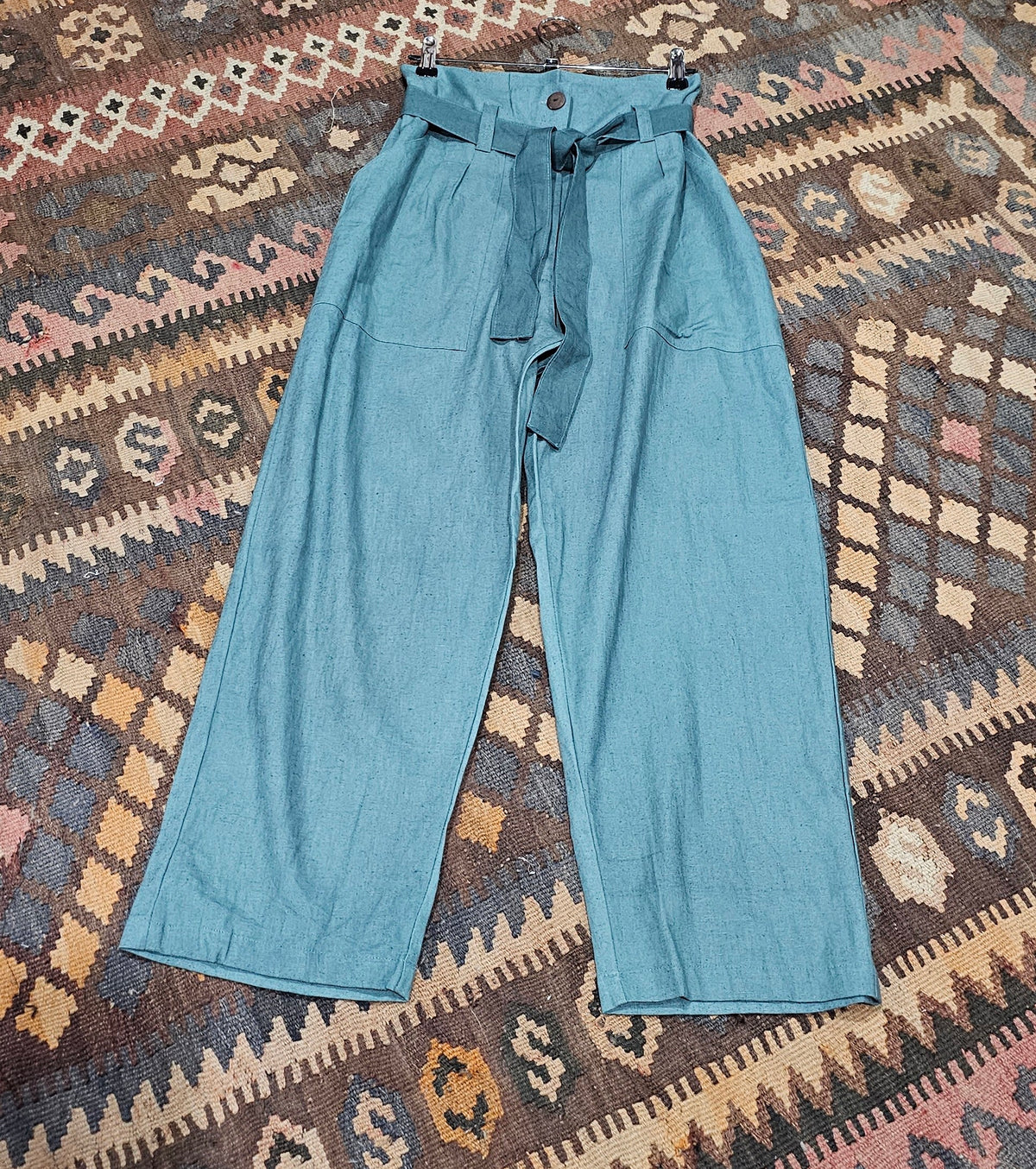 "High-waisted, super baggy cropped pants in a hand-dyed cotton linen blend with front pleats, pockets, zip closure, and a waist-accentuating belt."