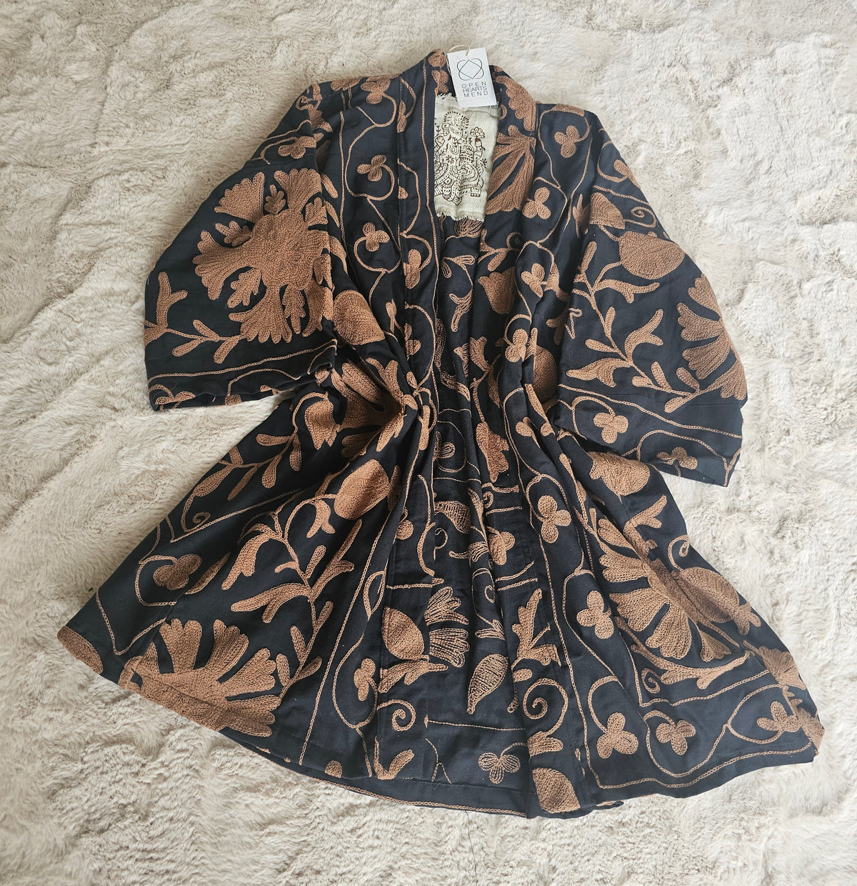 Hand-embroidered Suzani Taurus Flower Coat by Open Hearts Mend. Unique floral designs, outsize fit for sizes 10-20, one-of-a-kind craftsmanship. Perfect for adding artisanal elegance to your wardrobe.