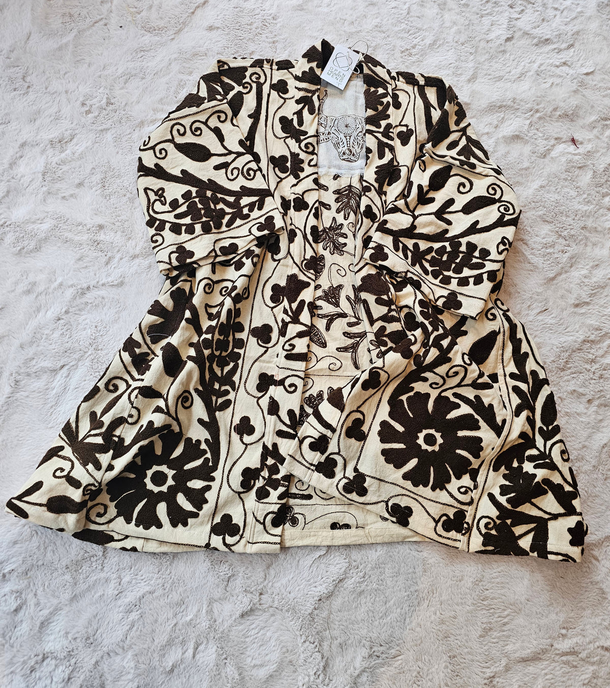 Hand-embroidered Suzani Taurus Flower Coat by Open Hearts Mend. Unique floral designs, outsize fit for sizes 10-20, one-of-a-kind craftsmanship. Perfect for adding artisanal elegance to your wardrobe.